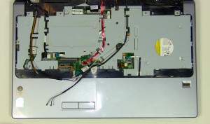 On the top of the laptop, pull the antenna cables through the motherboard and loosen them from the routing channels on the palm rest.