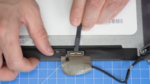 Use a plastic scribe to unclip and remove the LCD cable.