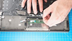 Peel away the tape to expose the upper touchpad screws.